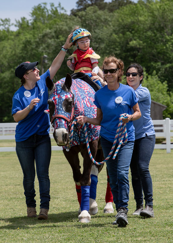 Volunteers Help child on horse